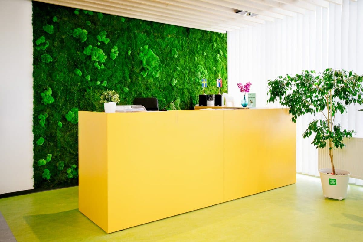 Empfangsbereich im IKEA Office mit gelbem Tresen und großformatiger Mooswand