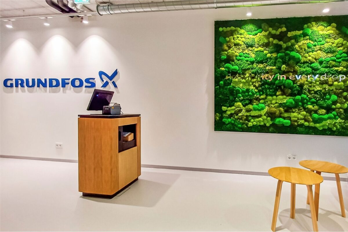 Markenraum: GRUNDFOS Logo und Mooswand von GREENIN im selben Raum – Corporate Identity.